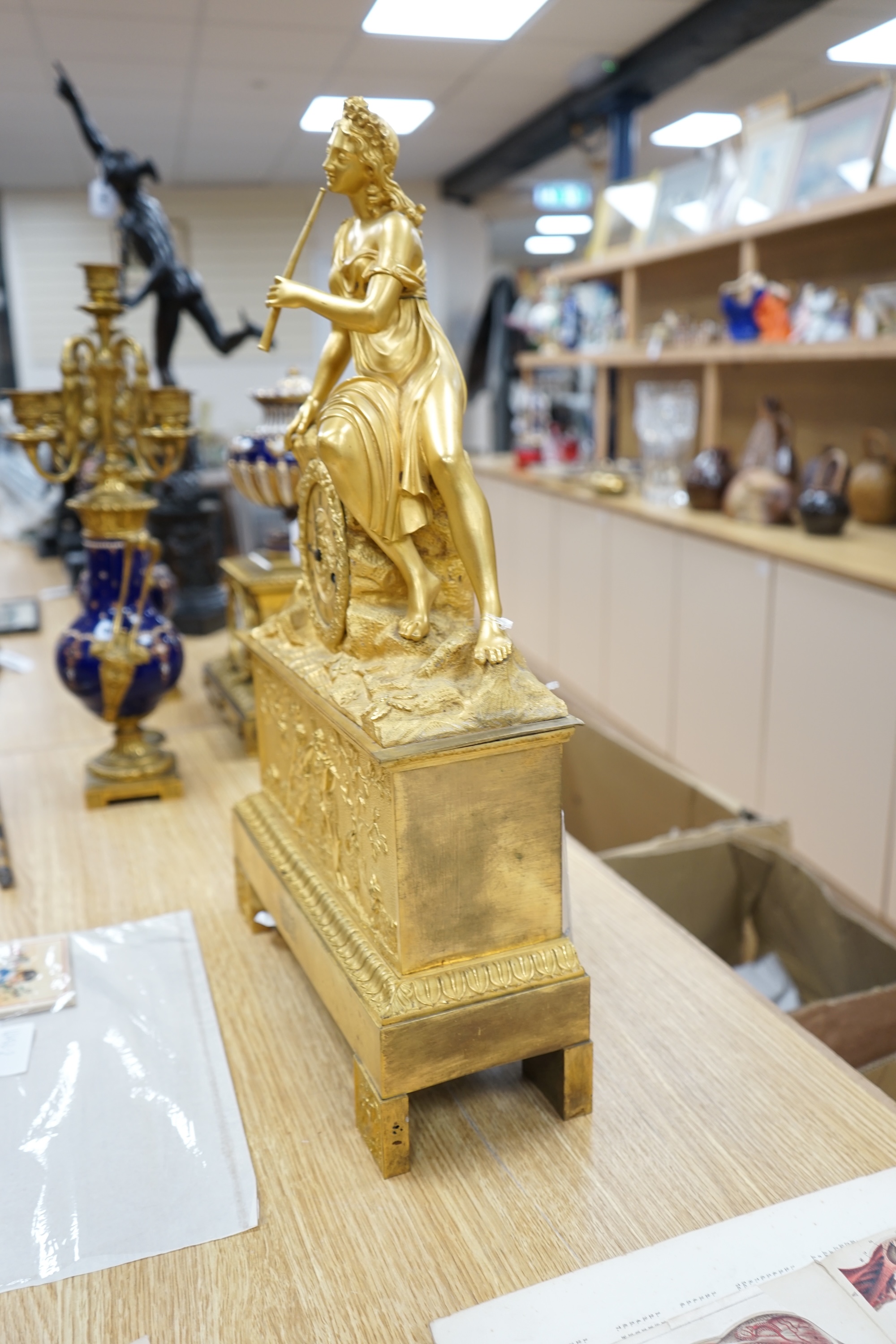 A French Louis Philippe period Empire ormolu clock, with seated classical female upon a rock enclosing the dial, the whole upon a square base with allegorical patch in relief, c.1830, with key, 57cm high. Condition - fai